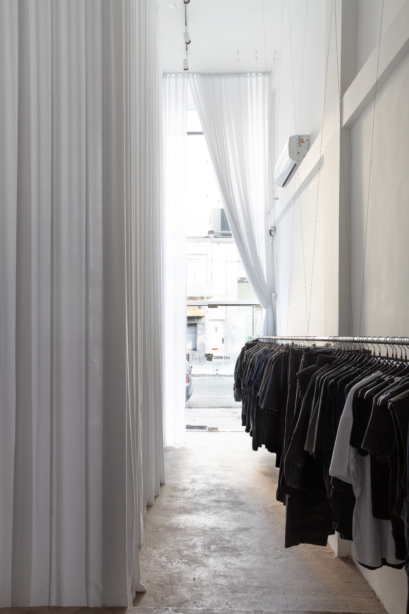 Interior del local Kabrakuervo con cortinas blancas y perchero de ropa